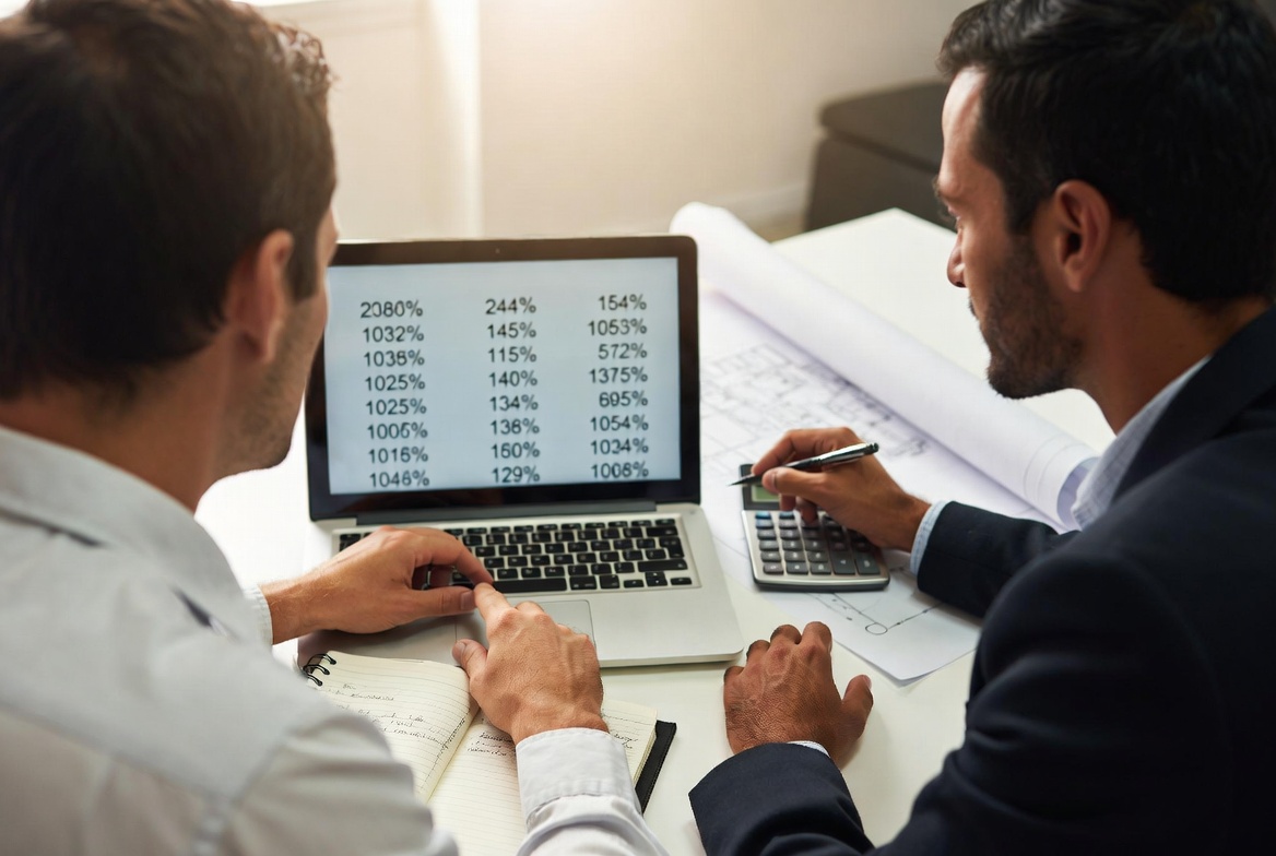 Advisor and investor reviewing real numbers together with blueprints on the desk